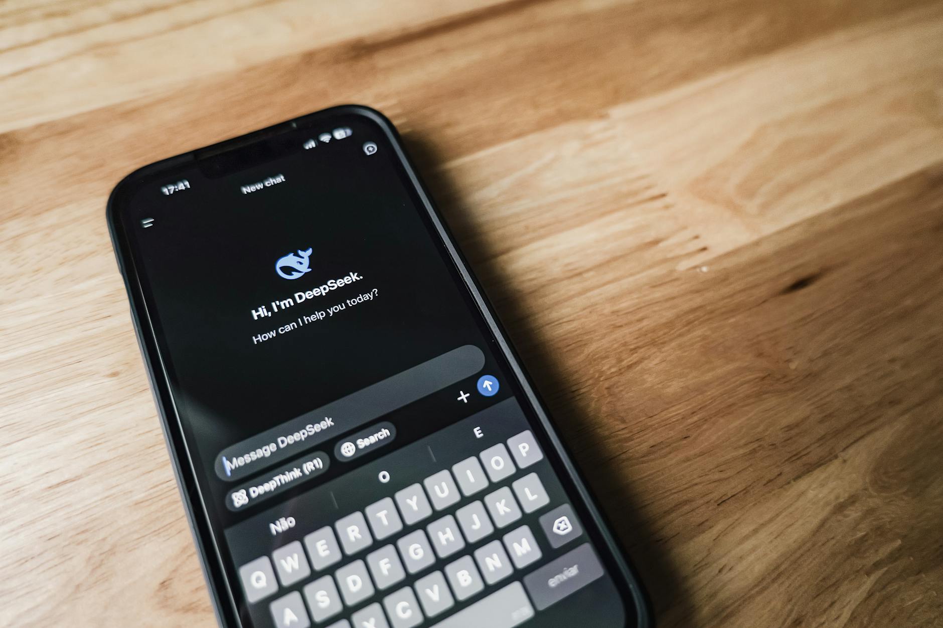Gros plan d'un smartphone montrant une interface d'application de chat sur une table en bois. — chatbot réseaux sociaux automatisation