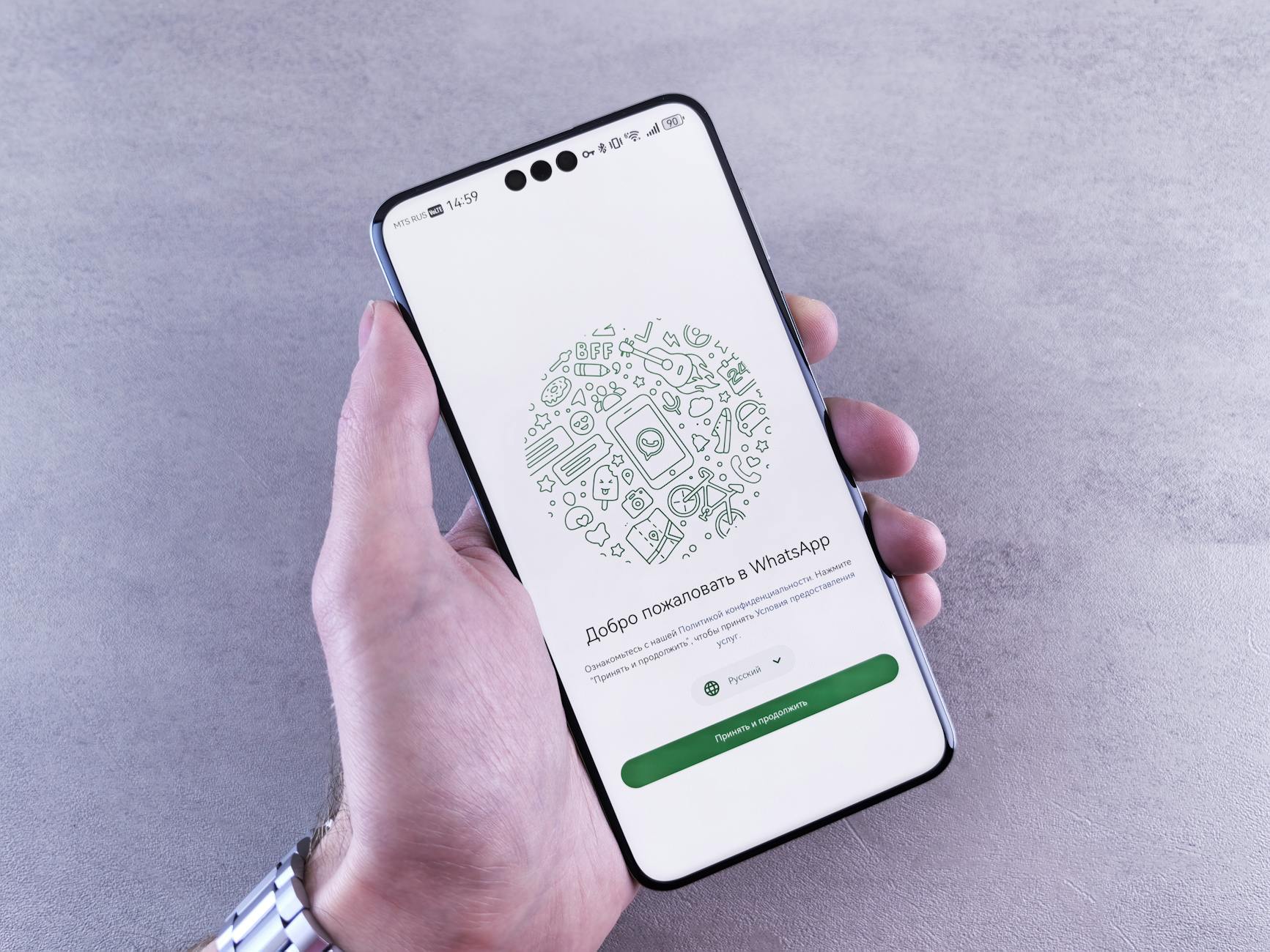 Gros plan d'une main tenant un smartphone affichant l'écran de bienvenue de WhatsApp en russe. — coût chatbot whatsapp