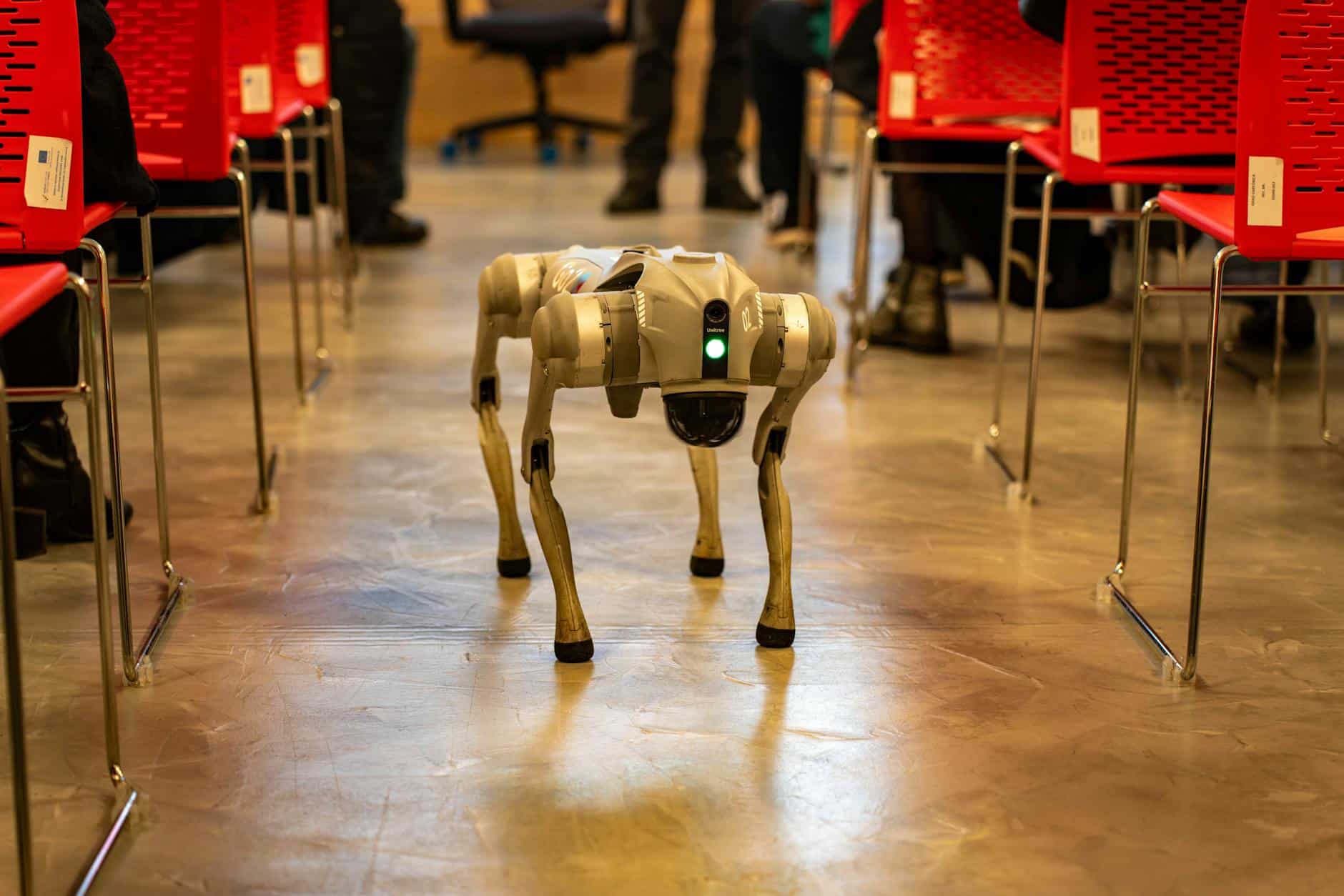 Un chien robotisé navigue dans un décor intérieur au milieu de chaises rouges, mettant en valeur la technologie dans des environnements modernes. — automatisation workflows ia